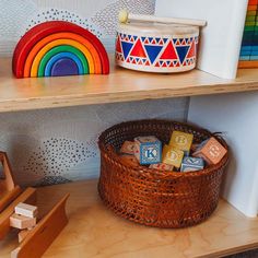 a wooden shelf filled with lots of toys on top of a floor next to a rainbow wall