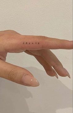 a woman's hand with the word create tattooed on her thumb and index finger