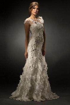 a woman in a white wedding dress with flowers on the bouncy skirt, standing against a dark background