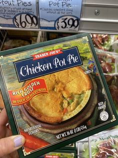 a close up of a person holding a box of chicken pot pie in a store