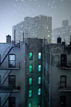 an apartment building is lit up with green lights in the snow at night, as if it were raining