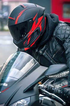 a man wearing a black leather jacket and helmet on a motorcycle