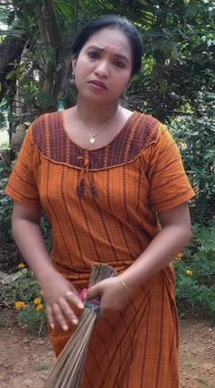 a woman in an orange dress holding some flowers