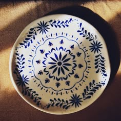 a blue and white plate sitting on top of a brown cloth covered table next to a window