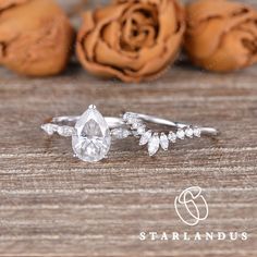 a close up of a diamond ring on a wooden table with roses in the background