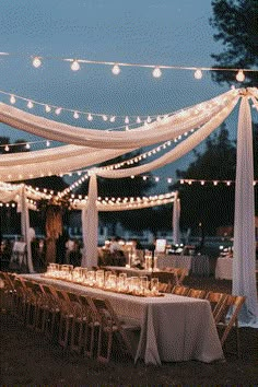 an outdoor wedding reception with white draping and string lights