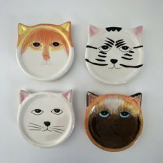 four plates with cats painted on them and one has a cat's head in the middle