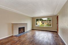 an empty living room with wood floors and a fireplace