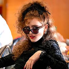 a woman with red hair and sunglasses sitting in a chair