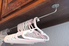 two white hangers are hanging from the ceiling in front of a wooden cabinet with drawers