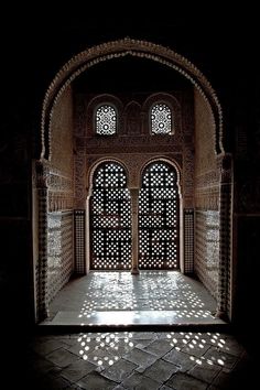 an open door in the middle of a room with tile flooring and arches on either side