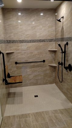 a walk in shower sitting next to a wooden bench and tiled walls with shelves on each side