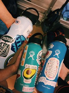 two people are holding water bottles with stickers on them