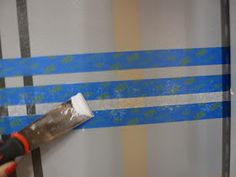 a person using a paint roller to paint a wall with blue and white stripes on it