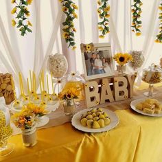 a baby shower table with sunflowers, cookies and other food on it's side