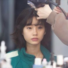 a woman is getting her hair done at the same time as she looks in the mirror