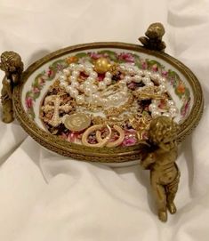 there is a decorative tray with pearls and other things in it on the white sheet