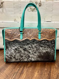 Spice up your style with the Tylersburg Hand Tooled Turquoise Handbag! This cow print and hair on hide bag is hand tooled with genuine leather and features a stunning turquoise color. Upgrade your accessory game and stand out from the herd. *ALL HIDES WILL VARY Materials Hairon & Leather Item Width 14 Item Height 10 Turquoise Handbags, Cowhide Purse, Whip Stitch, Cowhide Bag, Cow Hide, Turquoise Color, Leather Items, Cow Print, Western Style