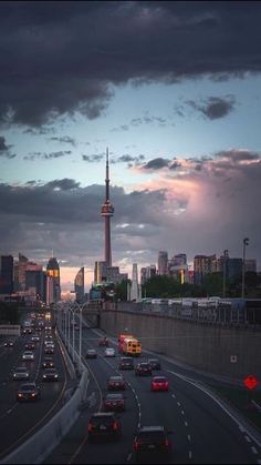 the city skyline is lit up at night with cars driving on the road in front of it