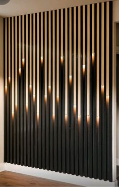 some candles are lit in front of a black and white striped wall with wood slats