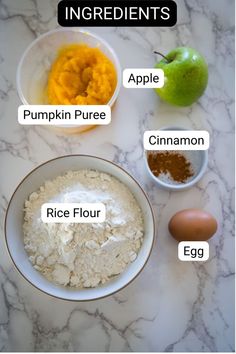 ingredients for pumpkin puree in bowls on a marble countertop with an apple, cinnamon, egg and flour