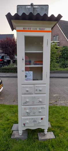 a white cabinet sitting on top of a lush green field next to a parking lot