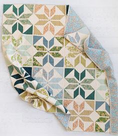 an old quilt is laying on top of a white surface with blue, green and orange designs