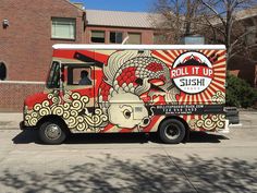 a food truck parked in front of a brick building with an advertisement on the side