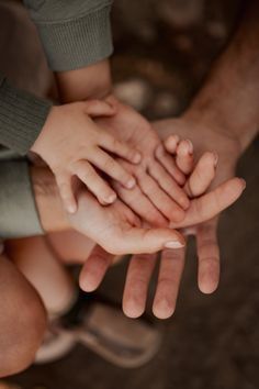 several people holding their hands together to form a stack on top of eachother