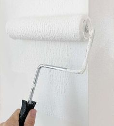 a person is using a paint roller to paint a wall with white paint on it