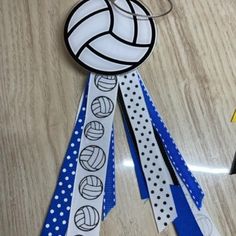 a volleyball medal with ribbons attached to it on top of a wooden table next to scissors