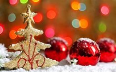 three christmas ornaments sitting on top of snow covered ground with boke lights in the background