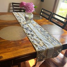 a vase with pink flowers sitting on top of a table next to two place mats