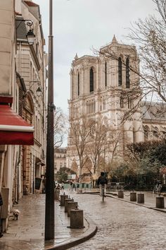 people are walking down the cobblestone street in front of an old cathedral