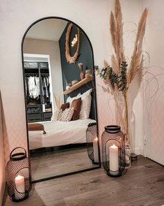 a mirror sitting on top of a wooden floor next to a vase filled with flowers