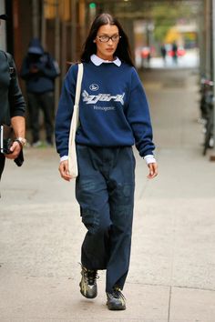 a woman walking down the street wearing a blue sweatshirt