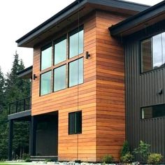 two story house with wood siding and glass windows on the front, surrounded by green grass