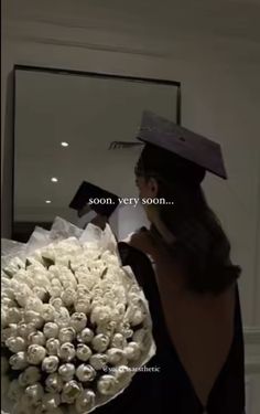 a woman wearing a graduation cap and gown holding a bouquet of flowers in her hand