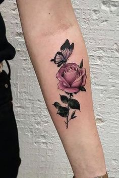 a woman's arm with a pink rose and butterfly tattoo on the left forearm