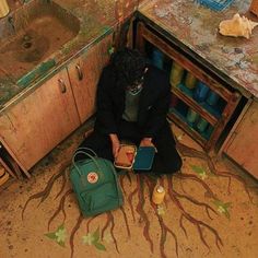 a woman sitting on the floor in front of a sink holding a small green bag