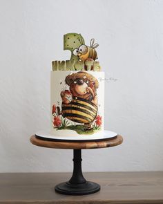 a three tiered cake decorated with an image of a bee and the letter b