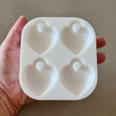 a hand holding a heart shaped ice tray with four hearts in the shape of two