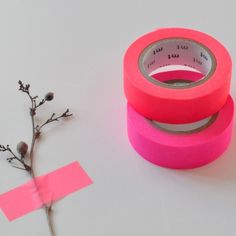 two rolls of pink tape sitting next to each other on top of a white surface