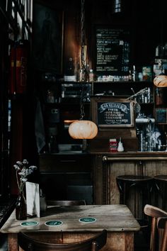 a table and chairs in a room with lights hanging from the ceiling over it's bar area