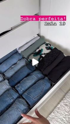 a drawer with several pairs of jeans in it and a hand pointing at the bottom