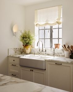 a kitchen with marble counter tops and white cabinets, along with a window over the sink