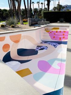 a skateboard park with colorful designs on the side and palm trees in the background