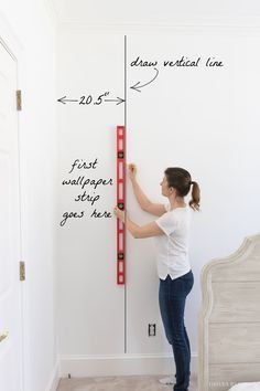 a woman is measuring the height of a wall