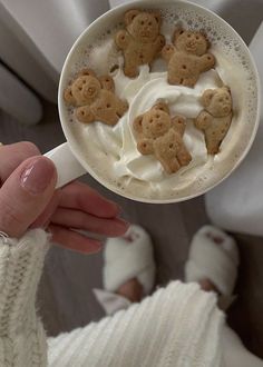 a person holding a cup filled with whipped cream and teddy bears