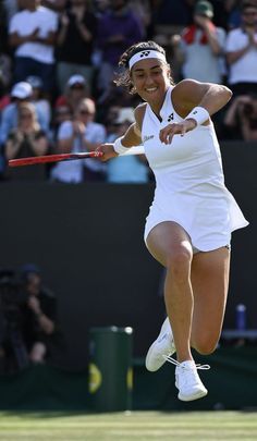 a woman swinging a tennis racquet on top of a grass covered tennis court